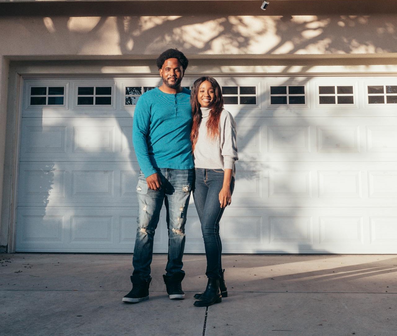 New homeowners smiling in front of their house.